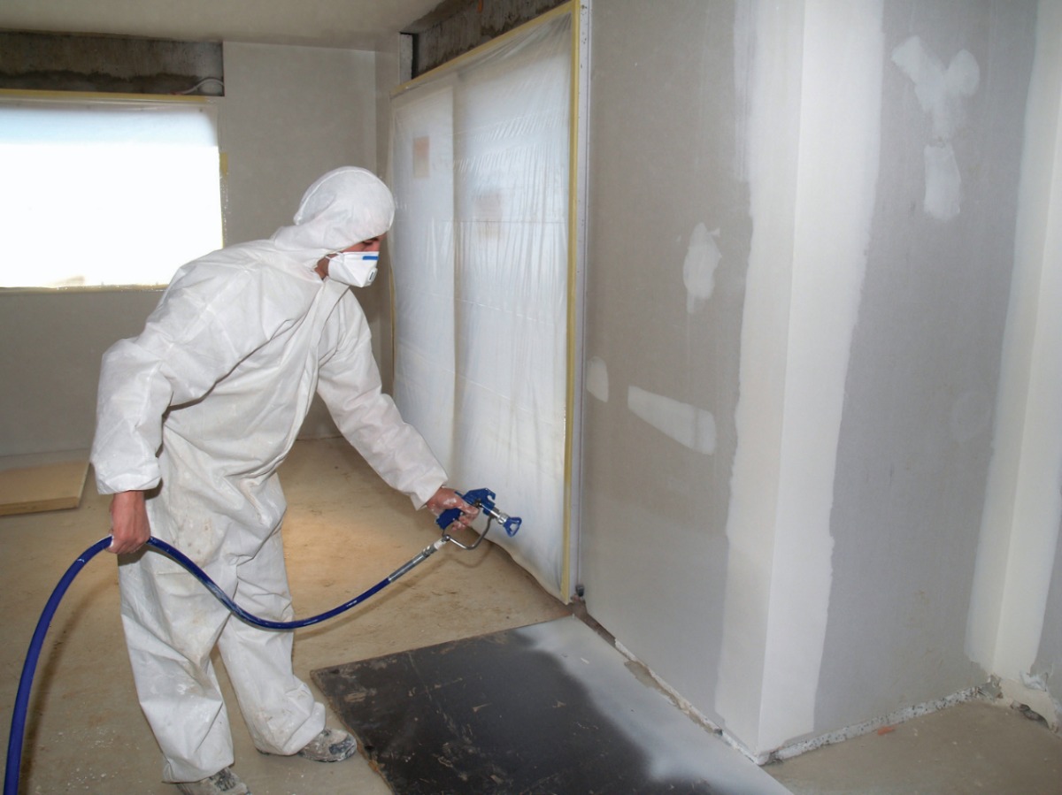 operador equipado e coberto utilizando a melhor maquina de pintura airless para pintar paredes internas