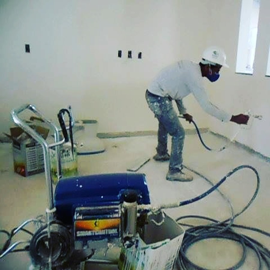 homem usando máquina de pintura airless em parede interna